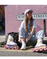 a photoshoot of a female skater who is wearing fuck you you fucking fuck white socks. sitting on the street, there is a pink wall as the background. she is wearing jeans coveralls and white t-shirt.